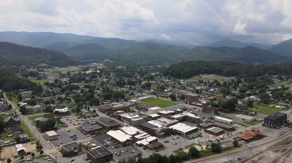 aerial view of the city with buildings among the trees, hills behind it