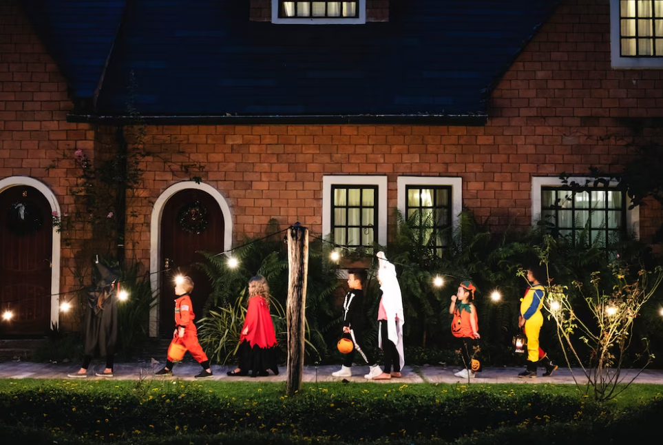 Group of kids with Halloween costumes and pumpkins on the street near the house